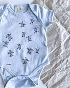 Baby blue organic cotton onesie with turtle hatchlings on it.