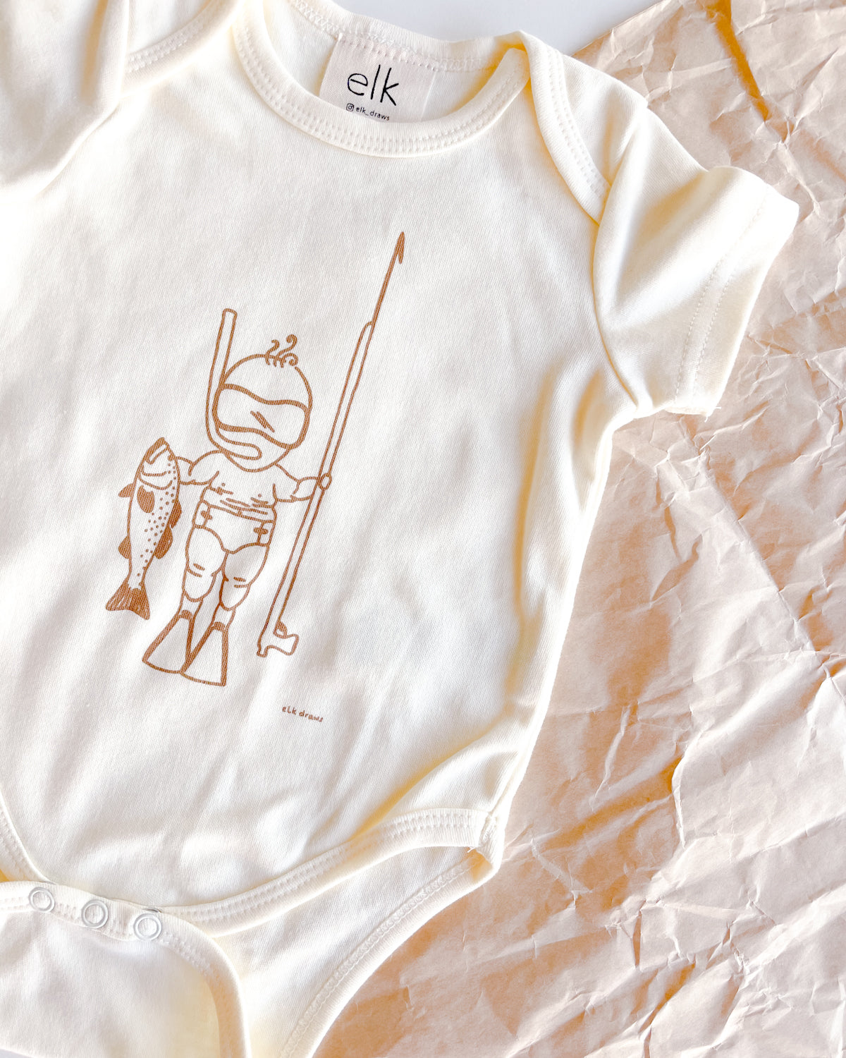 Baby Ecru organic cotton onesie with baby spearo on it.