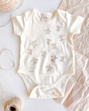 Load image into Gallery viewer, Baby ecru organic cotton onesie with turtle hatchlings on it.