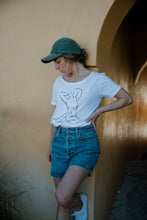 Load image into Gallery viewer, Girl standing in denim shorts wearing white organic cotton tshirt wth nude female form line art design on front by elk draws