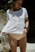Load image into Gallery viewer, Girl on beach in bathers in white organic cotton tshirt wth nude female form line art design on front by elk draws