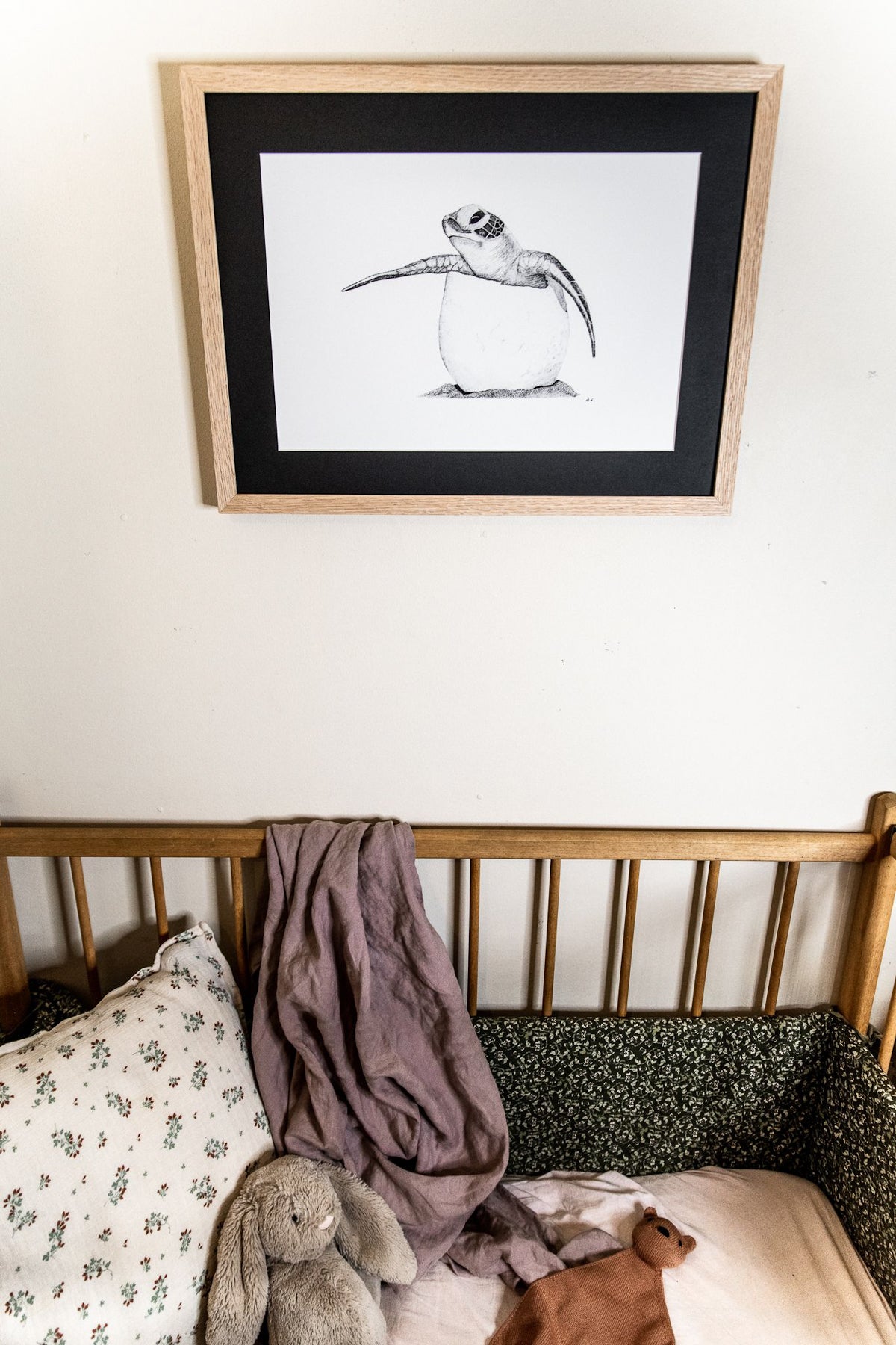 Baby turtle print hanging on wall above cot in nursery