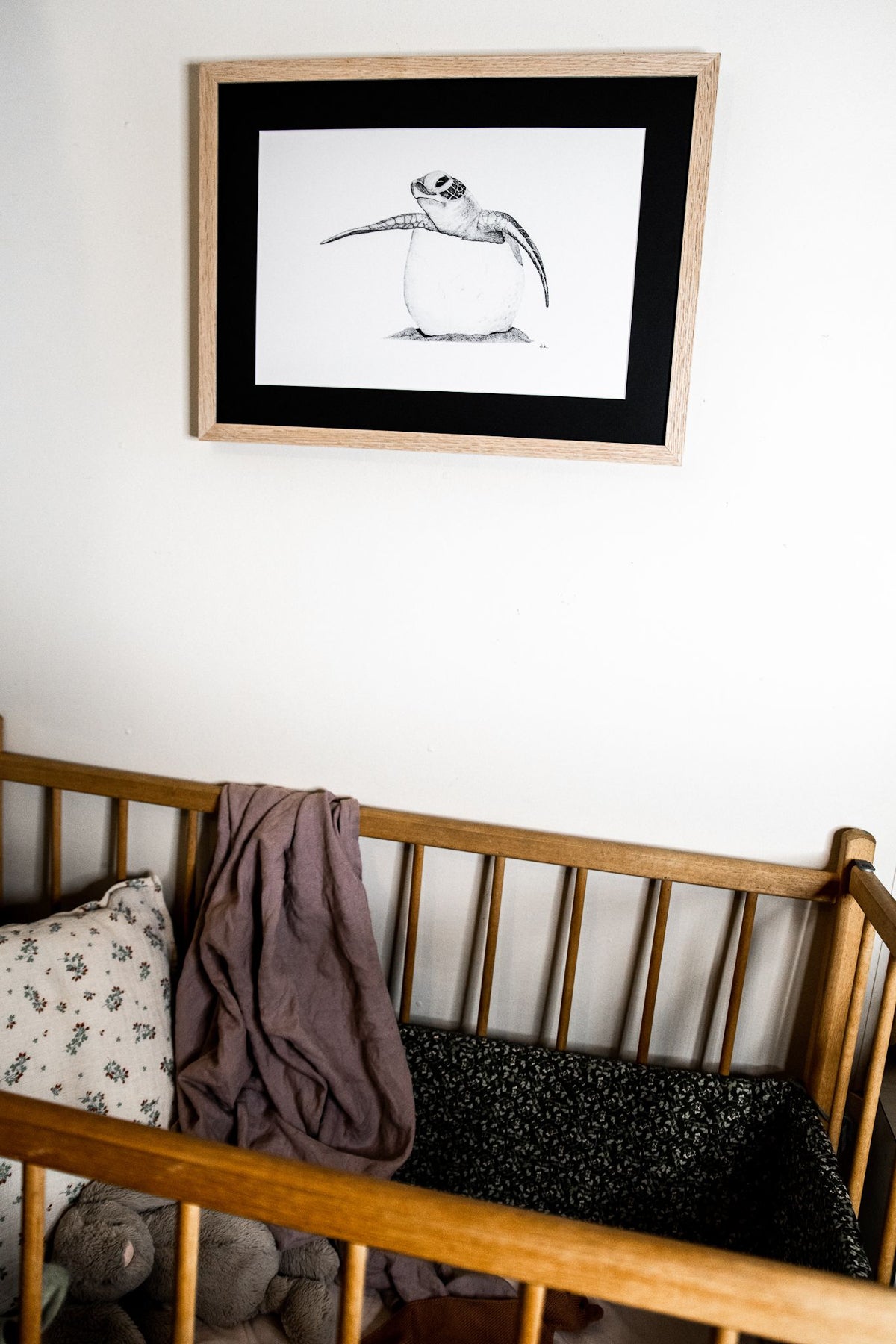 Baby turtle print hanging on wall above cot in nursery