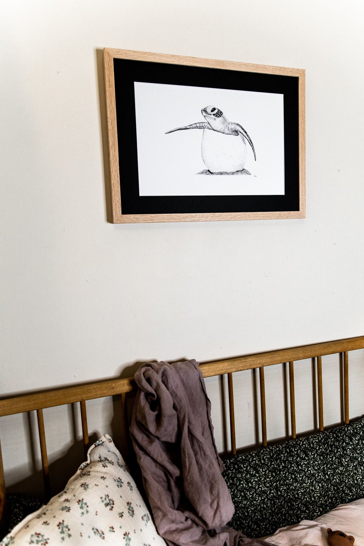 Baby turtle print hanging on wall above cot in nursery