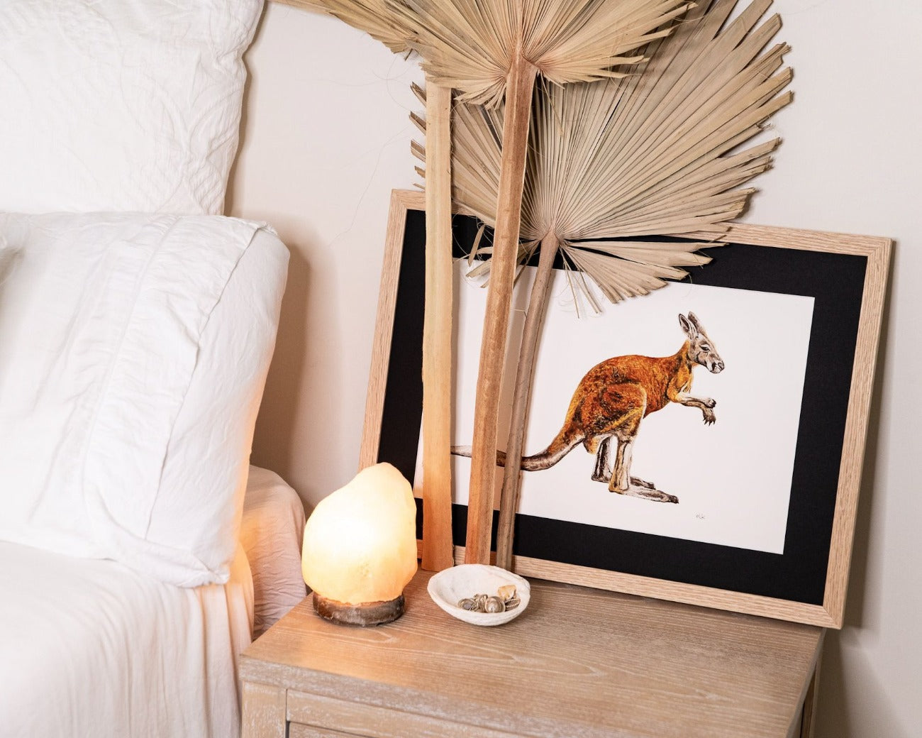 Kangaroo print on side table of white linen bed