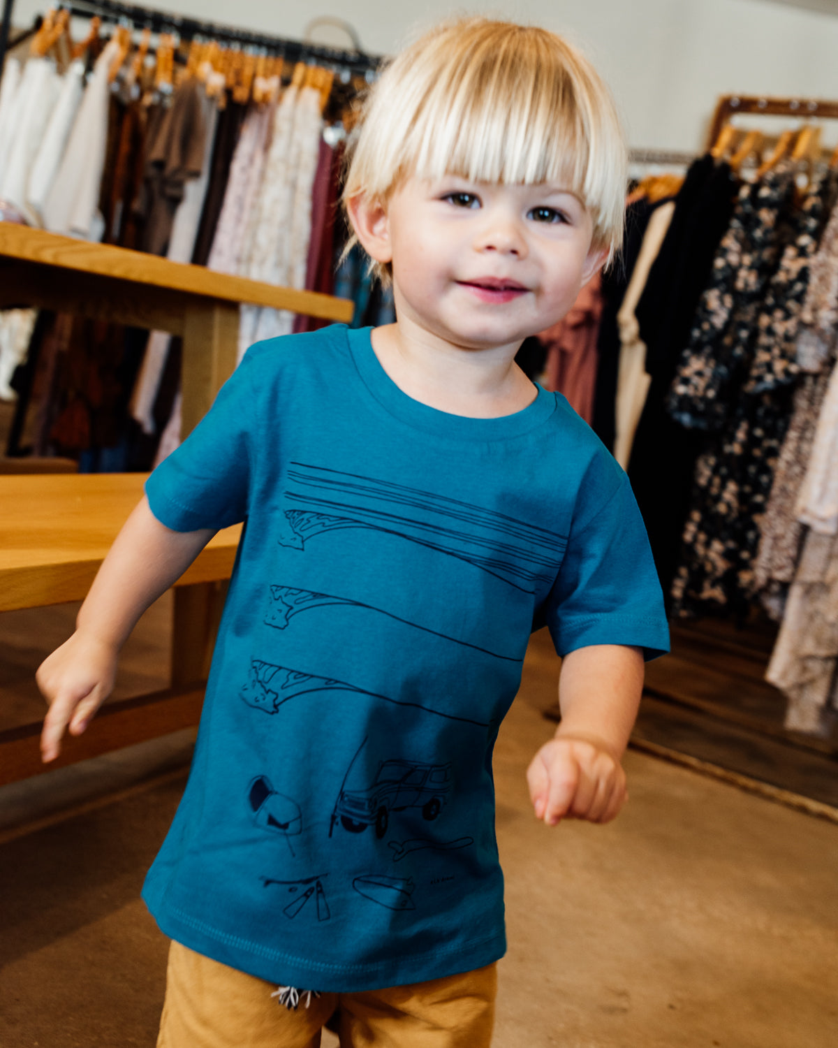 Young boy wearing blue elk draws organic cotton tshirt with troopy camping on it. 