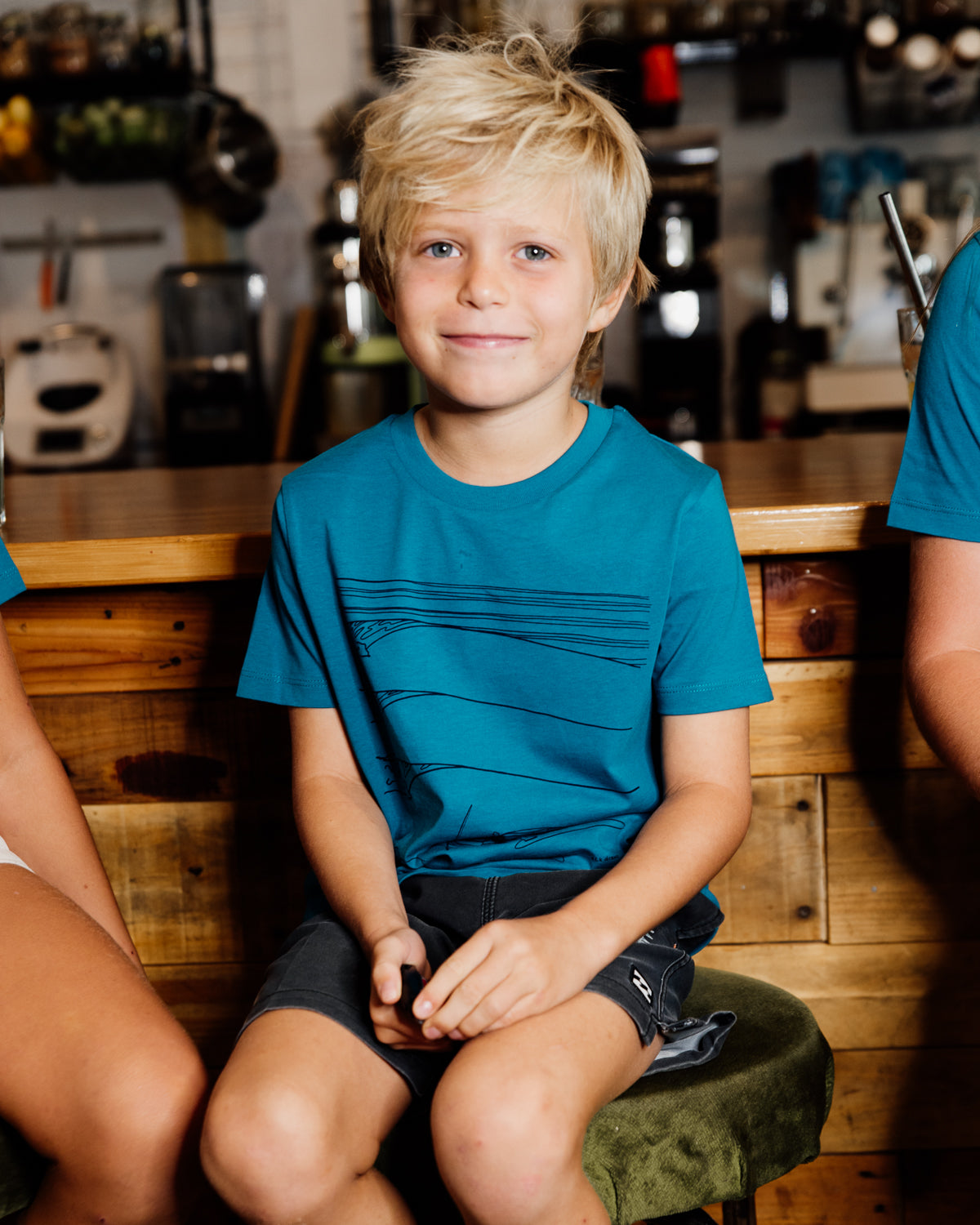 Young boy wearing blue elk draws organic cotton tshirt with troopy camping on it. 