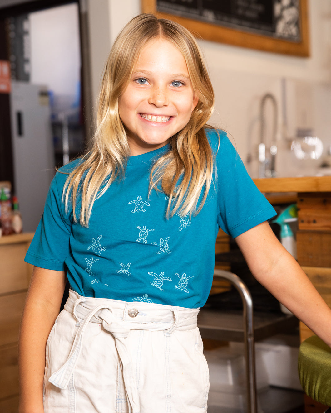 Young girl wearing blue organic cotton tshirt with turtle hatchlings on it.