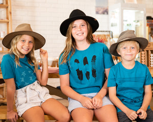 Three kids wearing elk draws organic cotton tshirts. 