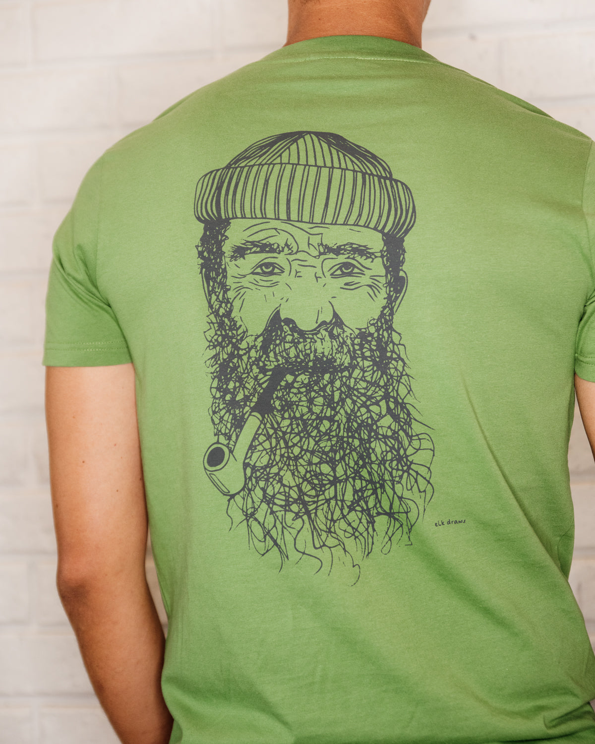 Male wearing elk draws green organic cotton tshirt with a Fisherman on it.