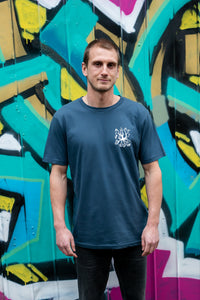 Man standing near graffiti with blue organic cotton tshirt with covid squid design by elk draws