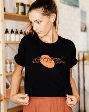 Load image into Gallery viewer, Female wearing elk draws black crop organic cotton tshirt with feather on it.